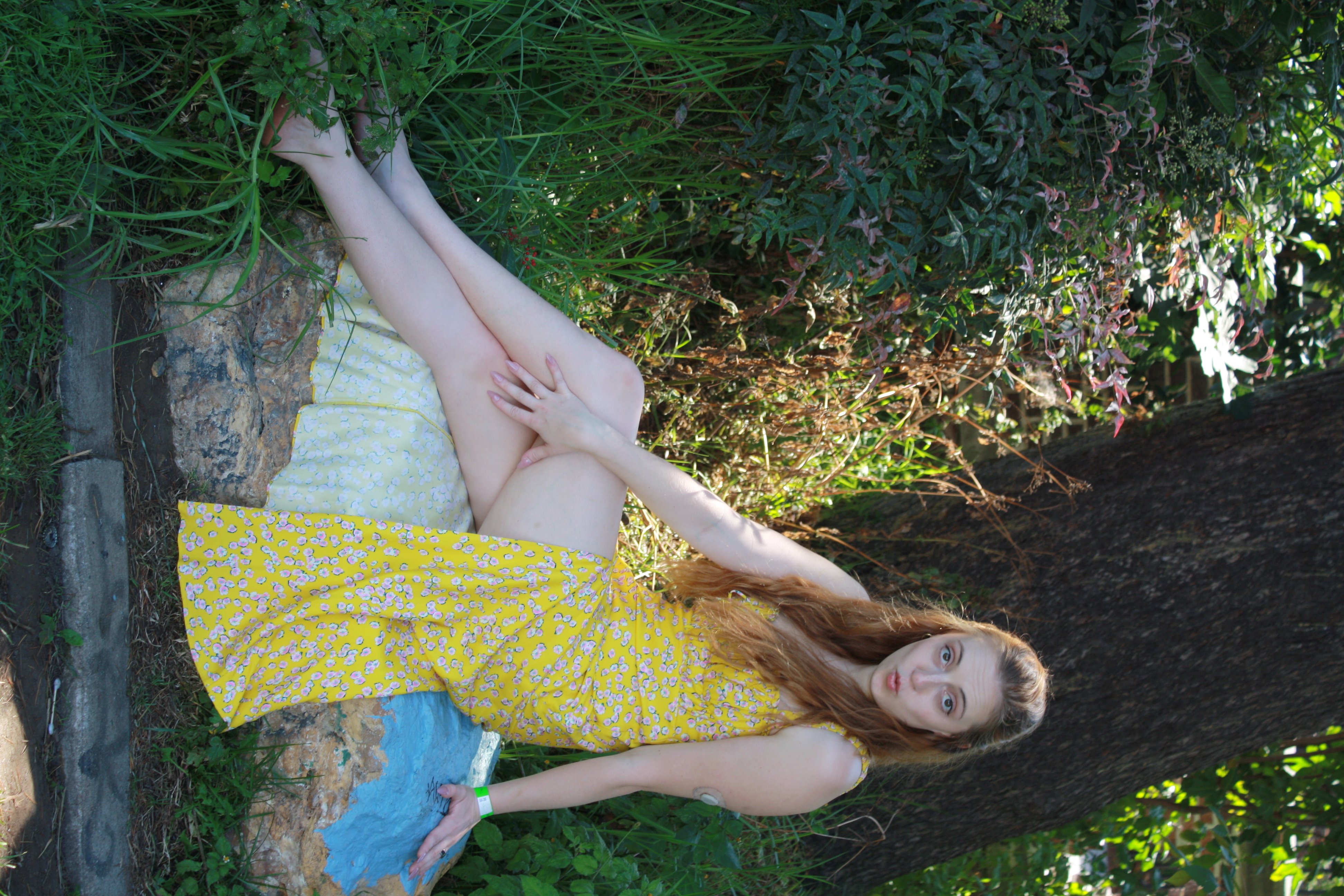 Jordie Morris sitting cross-legged on a rock at the Exposition Park Rose Garden